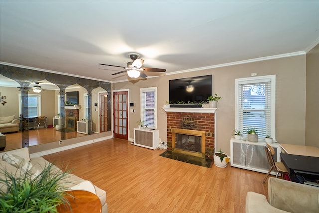 living room with ceiling fan, a brick fireplace, ornamental molding, and hardwood / wood-style flooring