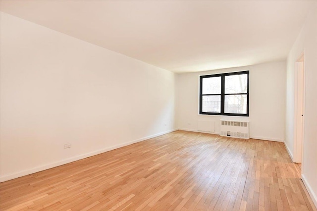 spare room with radiator heating unit and light hardwood / wood-style floors