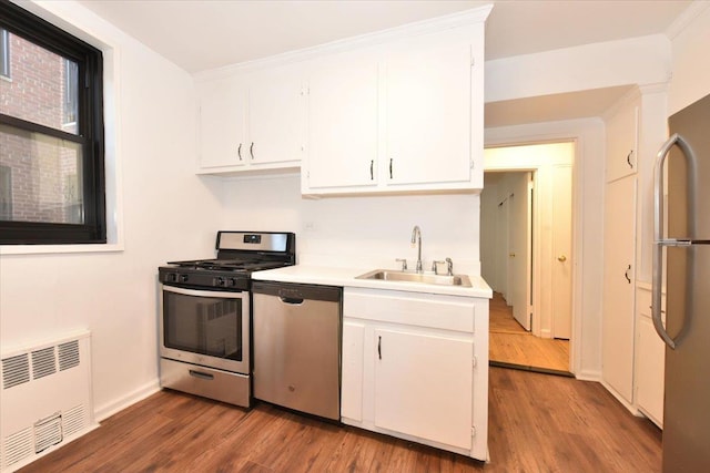 kitchen with white cabinets, radiator heating unit, sink, and appliances with stainless steel finishes