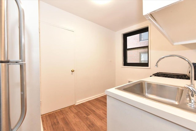 kitchen featuring white cabinetry, sink, and light wood-type flooring