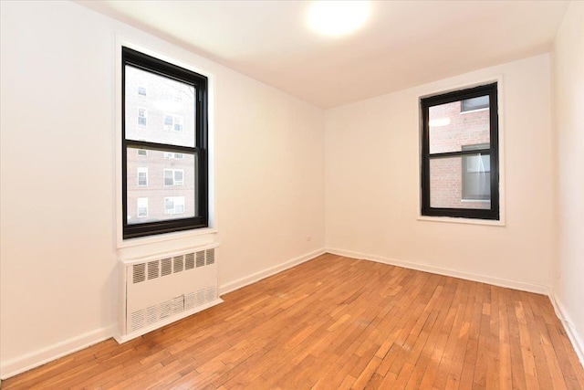 empty room featuring radiator and light hardwood / wood-style floors