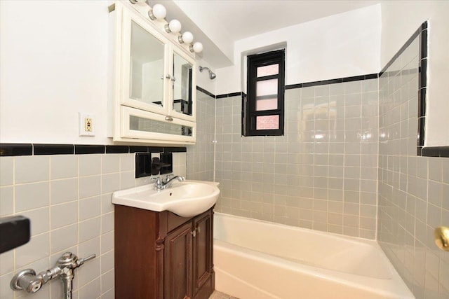 bathroom featuring tiled shower / bath, vanity, and tile walls