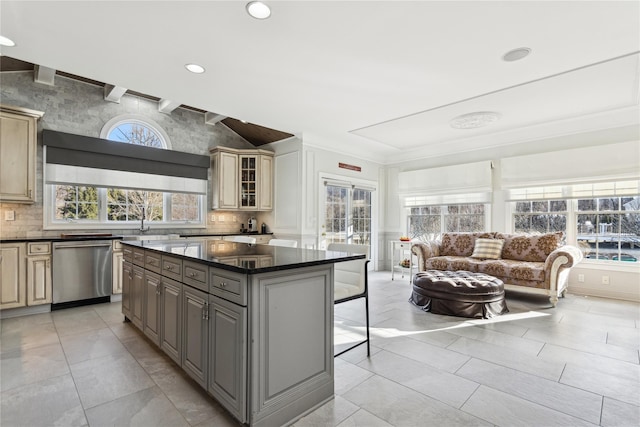 kitchen with gray cabinetry, a breakfast bar, a center island, stainless steel dishwasher, and tasteful backsplash