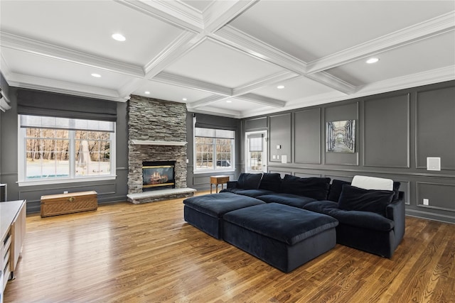 living room featuring coffered ceiling, crown molding, dark hardwood / wood-style floors, a fireplace, and beam ceiling