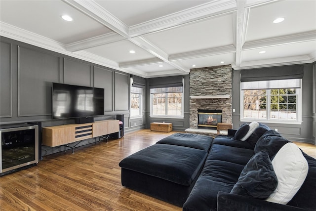 living room featuring beamed ceiling, a stone fireplace, dark hardwood / wood-style flooring, and beverage cooler