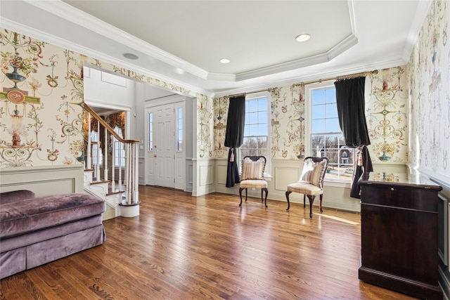 living area with a raised ceiling, crown molding, and hardwood / wood-style floors