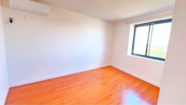 empty room featuring hardwood / wood-style floors and a wall mounted AC