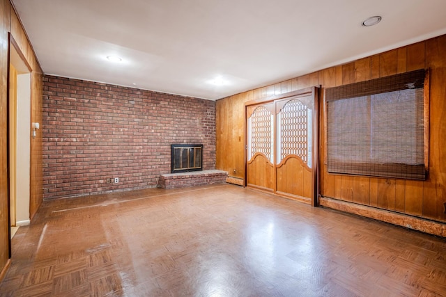 unfurnished living room featuring wooden walls, parquet floors, brick wall, and a brick fireplace