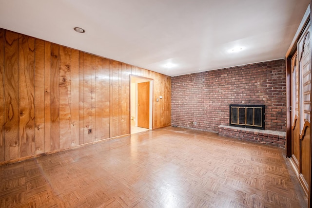 unfurnished living room with wooden walls, a fireplace, and parquet flooring