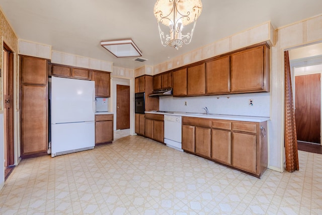 kitchen featuring pendant lighting, white appliances, sink, and a chandelier