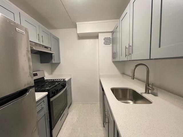 kitchen with stainless steel appliances, gray cabinetry, and sink