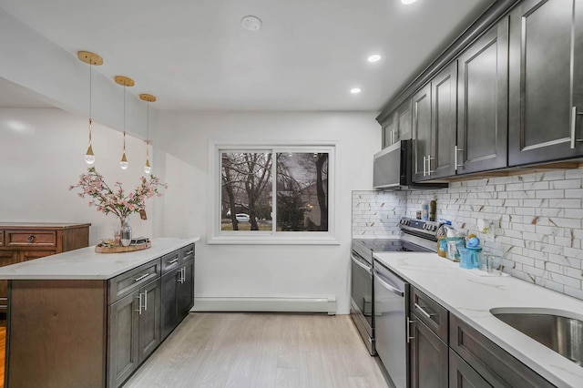 kitchen featuring stainless steel appliances, a baseboard heating unit, pendant lighting, decorative backsplash, and light wood-type flooring