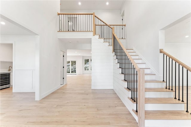 stairs with wine cooler, hardwood / wood-style floors, and ornamental molding