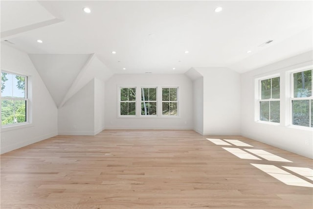 additional living space featuring plenty of natural light, lofted ceiling, and light wood-type flooring