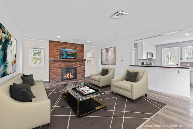 living room featuring dark hardwood / wood-style floors, crown molding, and a fireplace