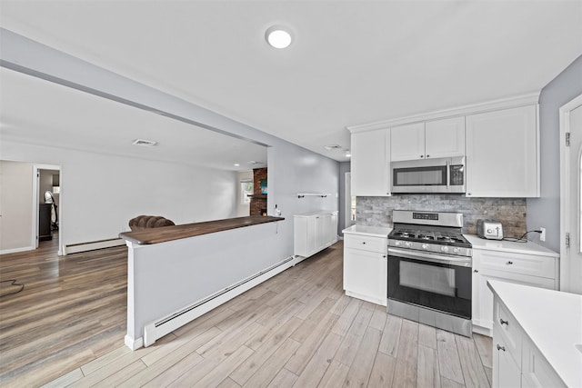 kitchen with decorative backsplash, white cabinets, stainless steel appliances, and a baseboard heating unit