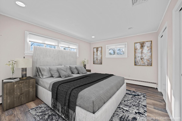 bedroom with dark hardwood / wood-style flooring, baseboard heating, and multiple windows