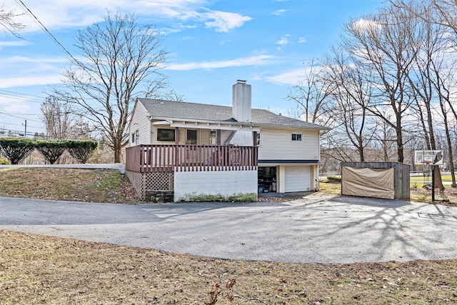 rear view of property with a garage and a wooden deck