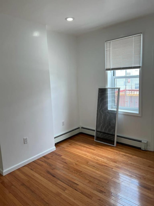 unfurnished room with light wood-type flooring and a baseboard heating unit