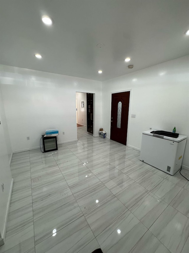 foyer entrance with baseboards and recessed lighting