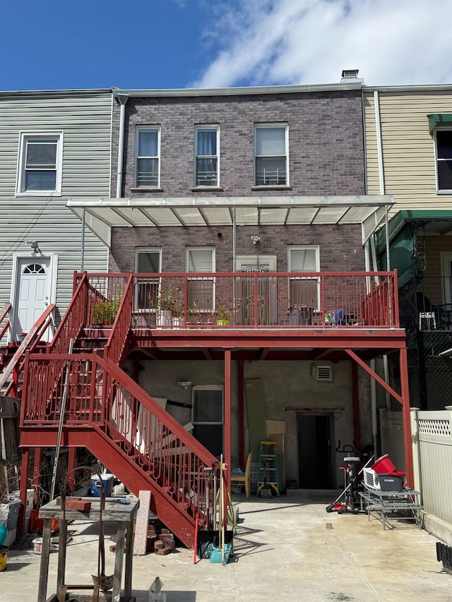 rear view of property with stairway, brick siding, and fence