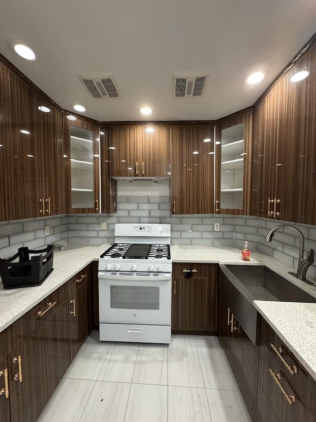 kitchen featuring decorative backsplash, a sink, white range with gas cooktop, and visible vents