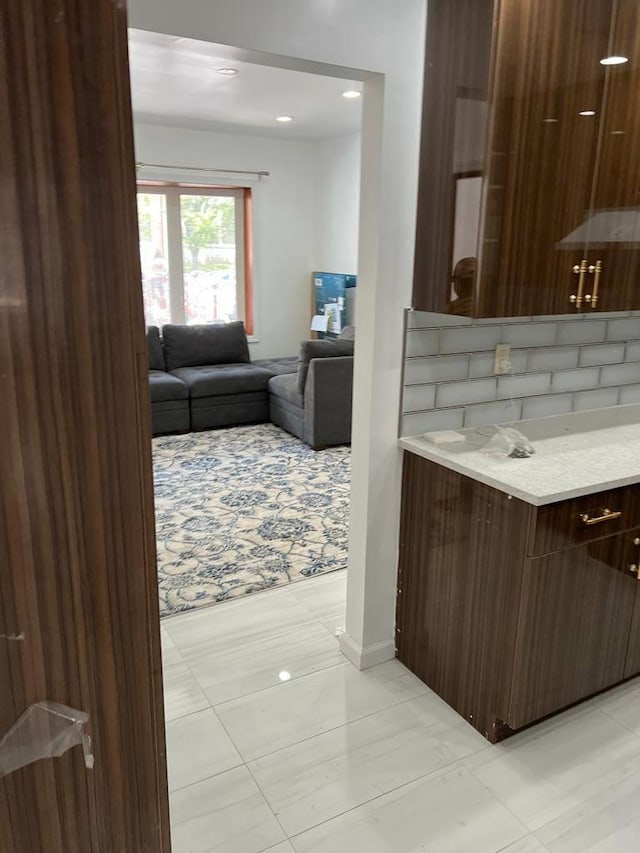 interior space featuring dark brown cabinets, light tile patterned floors, light stone counters, and modern cabinets