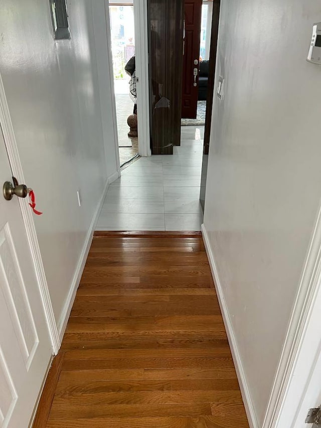 hallway featuring wood finished floors and baseboards