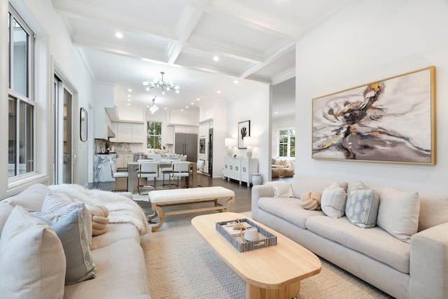 living room featuring hardwood / wood-style floors, beam ceiling, coffered ceiling, a notable chandelier, and ornamental molding