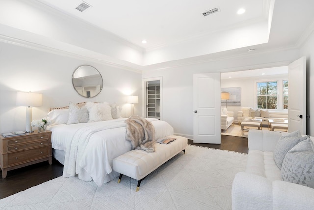 bedroom featuring crown molding, a walk in closet, a raised ceiling, and hardwood / wood-style floors