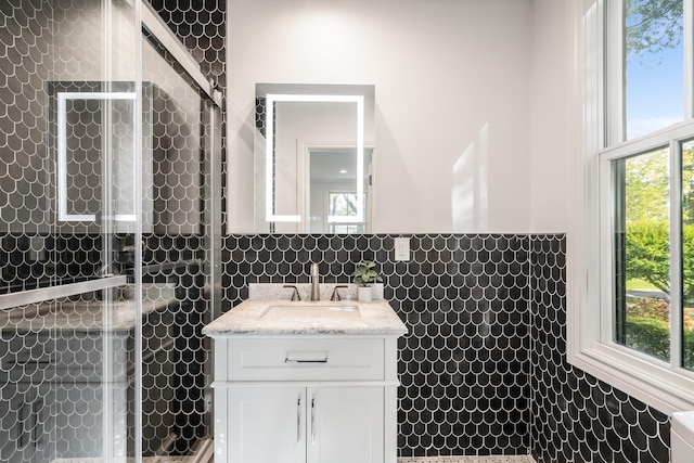 bathroom with plenty of natural light, a shower with shower door, and tile walls