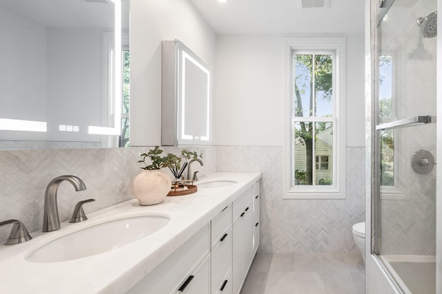 bathroom with vanity, tile patterned floors, tile walls, and toilet