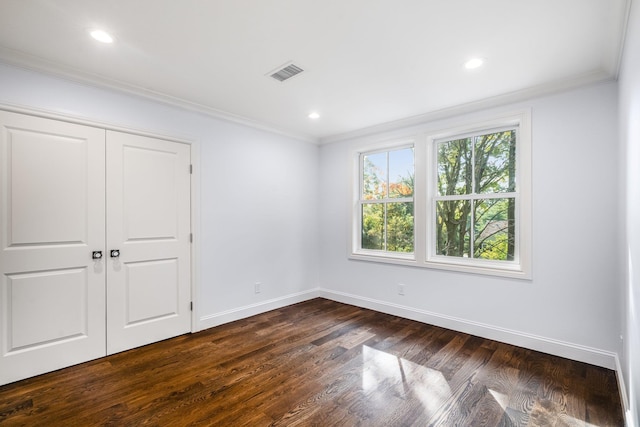 unfurnished bedroom with a closet, crown molding, and dark hardwood / wood-style floors