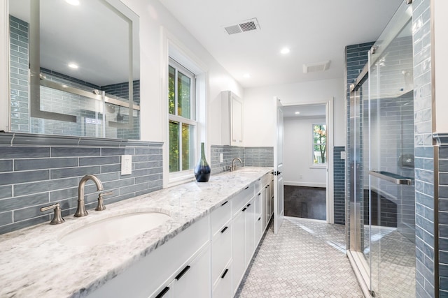 bathroom with vanity, decorative backsplash, tile patterned floors, and walk in shower