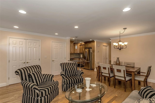 living room featuring ornamental molding, a notable chandelier, and light hardwood / wood-style flooring