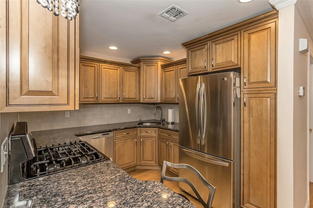 kitchen featuring light hardwood / wood-style floors, backsplash, dark stone counters, appliances with stainless steel finishes, and sink