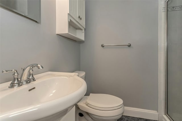 bathroom with toilet, a shower with shower door, and sink