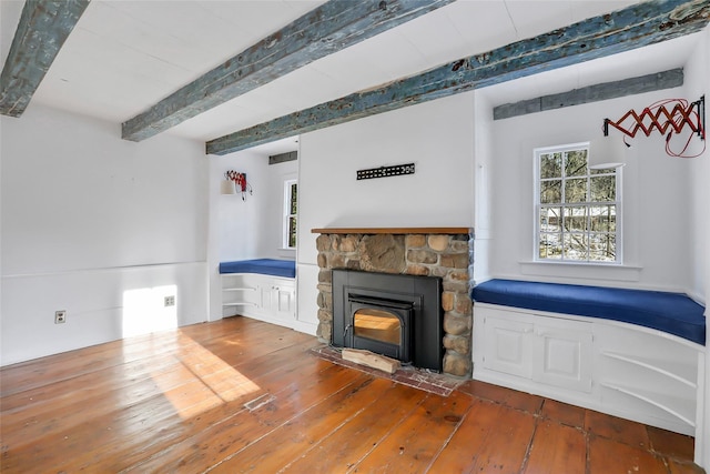 unfurnished living room featuring beamed ceiling, wood-type flooring, and a wood stove