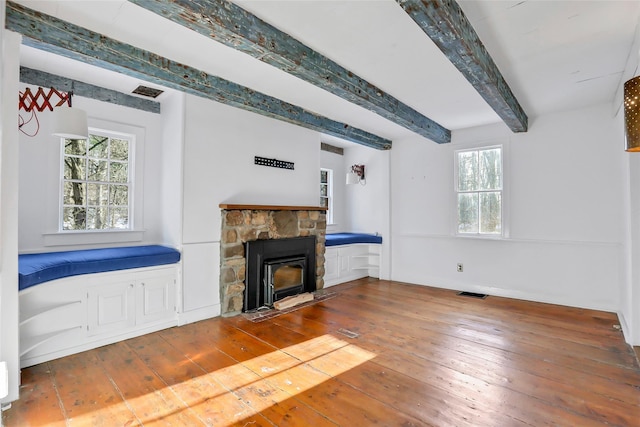 unfurnished living room featuring a fireplace, beamed ceiling, and hardwood / wood-style flooring