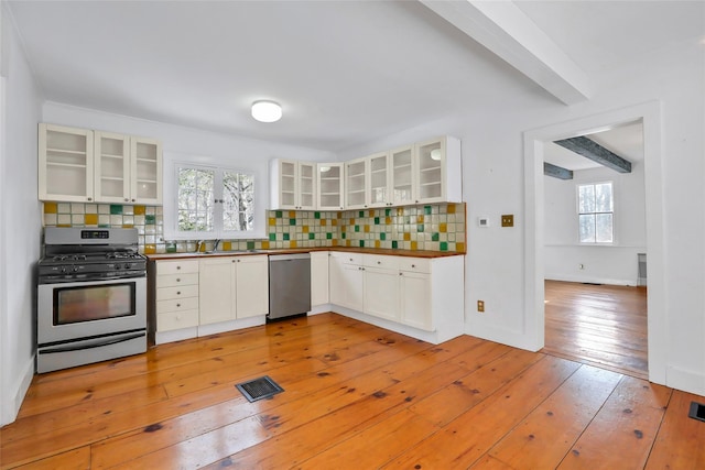 kitchen with decorative backsplash, light hardwood / wood-style floors, white cabinetry, and appliances with stainless steel finishes