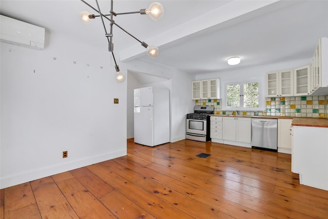 kitchen featuring white cabinets, an AC wall unit, tasteful backsplash, beam ceiling, and stainless steel appliances