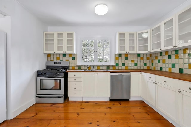 kitchen featuring decorative backsplash, appliances with stainless steel finishes, white cabinets, and sink