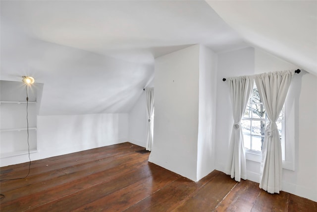 additional living space with dark hardwood / wood-style flooring and vaulted ceiling