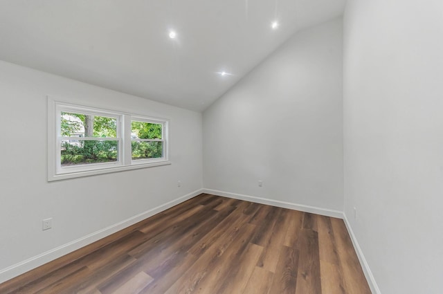 spare room with dark wood-type flooring and vaulted ceiling