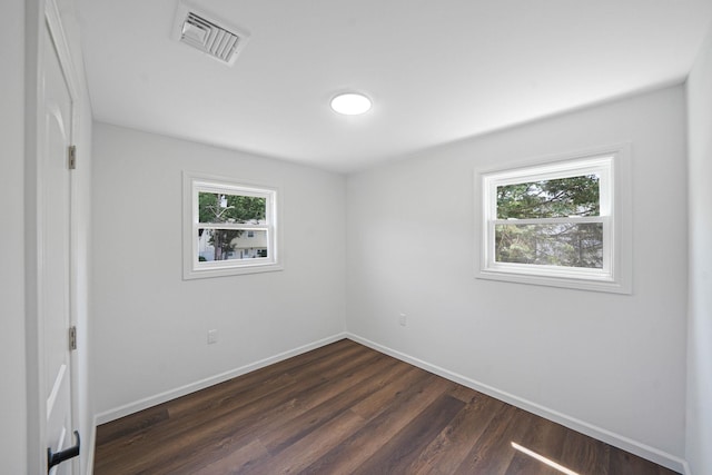 unfurnished bedroom with multiple windows and dark wood-type flooring