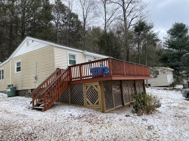 snow covered rear of property with a wooden deck