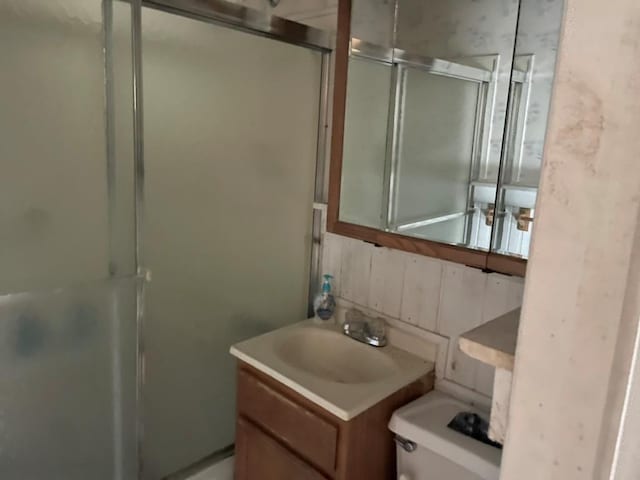 bathroom featuring toilet, a shower with door, and vanity