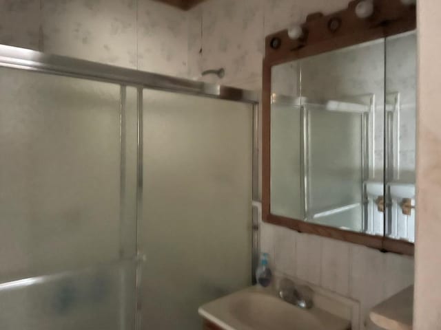 bathroom featuring sink, an enclosed shower, and decorative backsplash