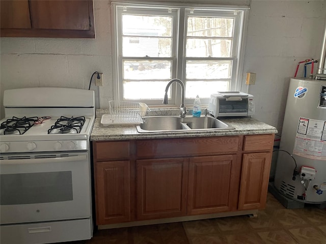 kitchen featuring water heater, white gas range, plenty of natural light, and sink