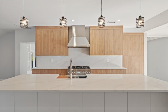 kitchen with light stone counters, hanging light fixtures, wall chimney range hood, and modern cabinets